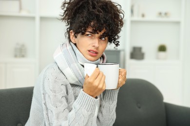 Photo of Cold symptom. Young woman with tissue and cup of hot drink at home