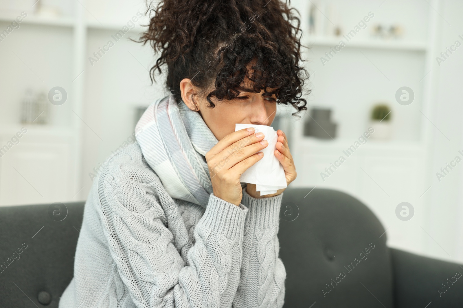 Photo of Cold symptom. Young woman with tissue at home