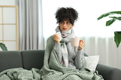 Cold symptom. Young woman with tissue and cup of hot drink at home