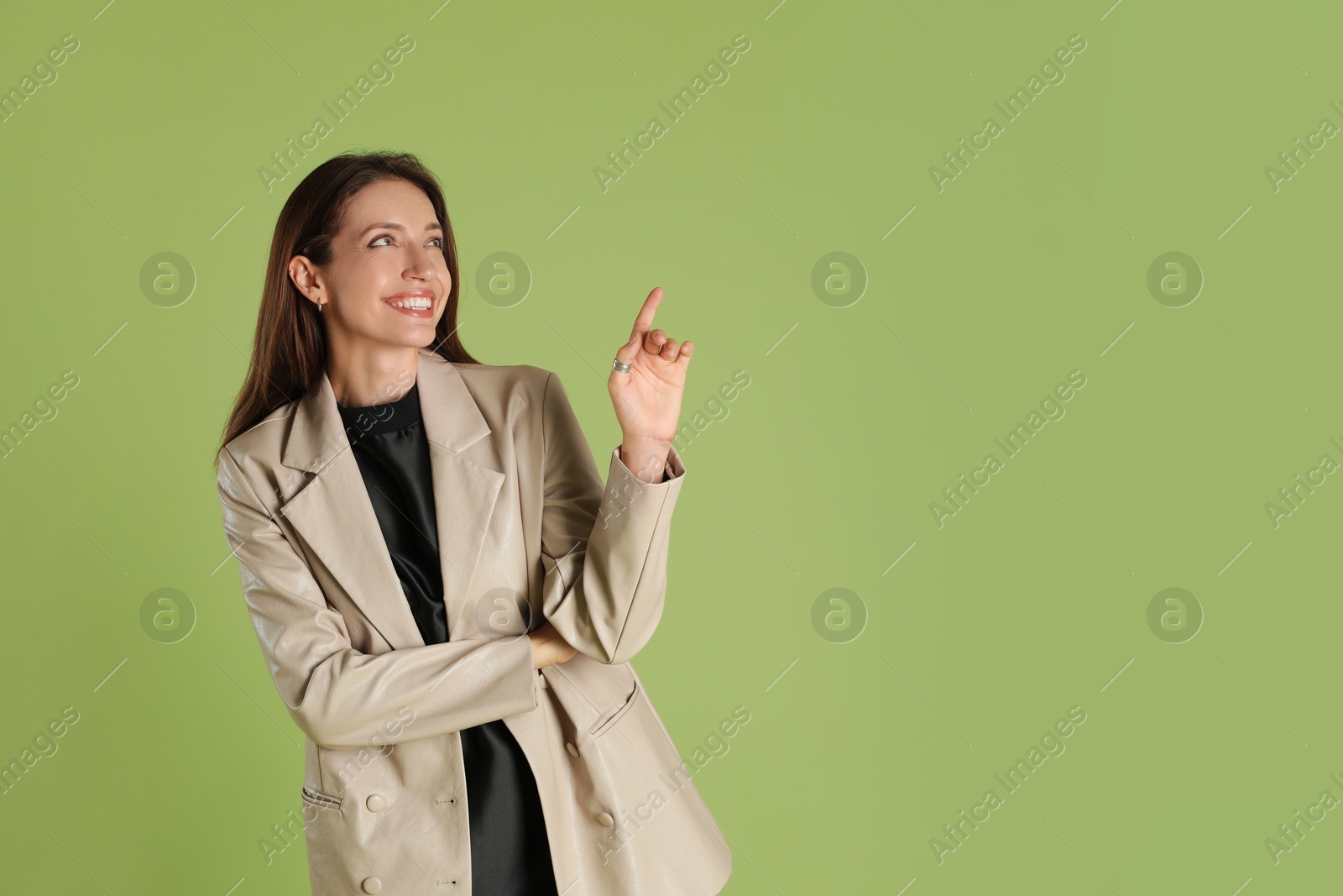 Photo of Beautiful woman in stylish beige jacket on olive background, space for text