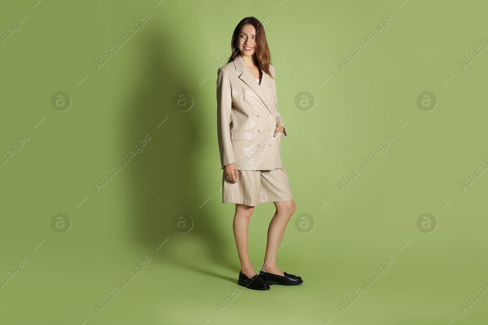 Photo of Beautiful woman in stylish beige suit on olive background