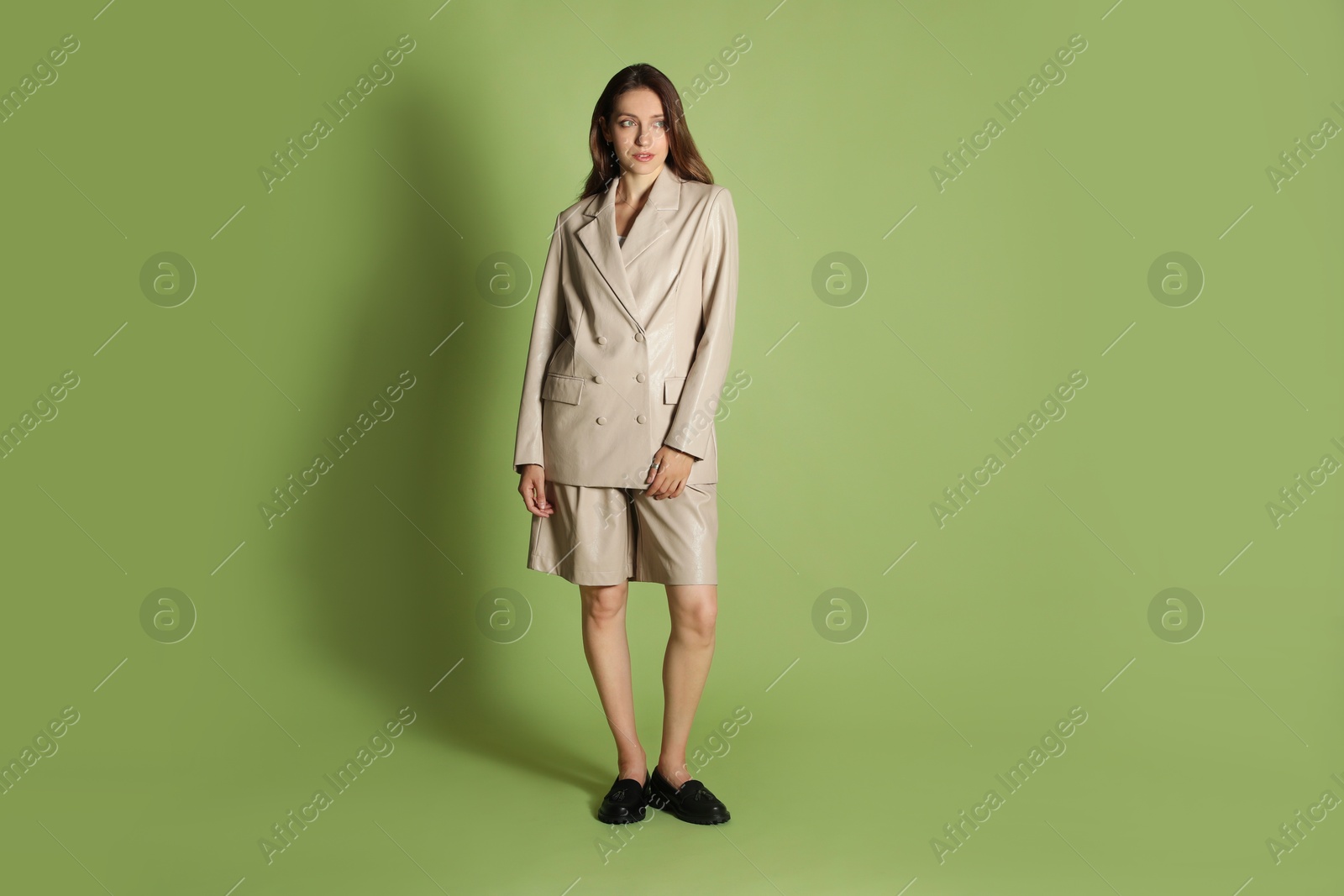 Photo of Beautiful woman in stylish beige suit on olive background, space for text