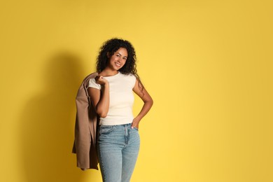 Photo of Beautiful woman with stylish jacket on yellow background, space for text