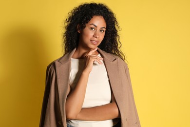 Beautiful woman with stylish jacket on yellow background