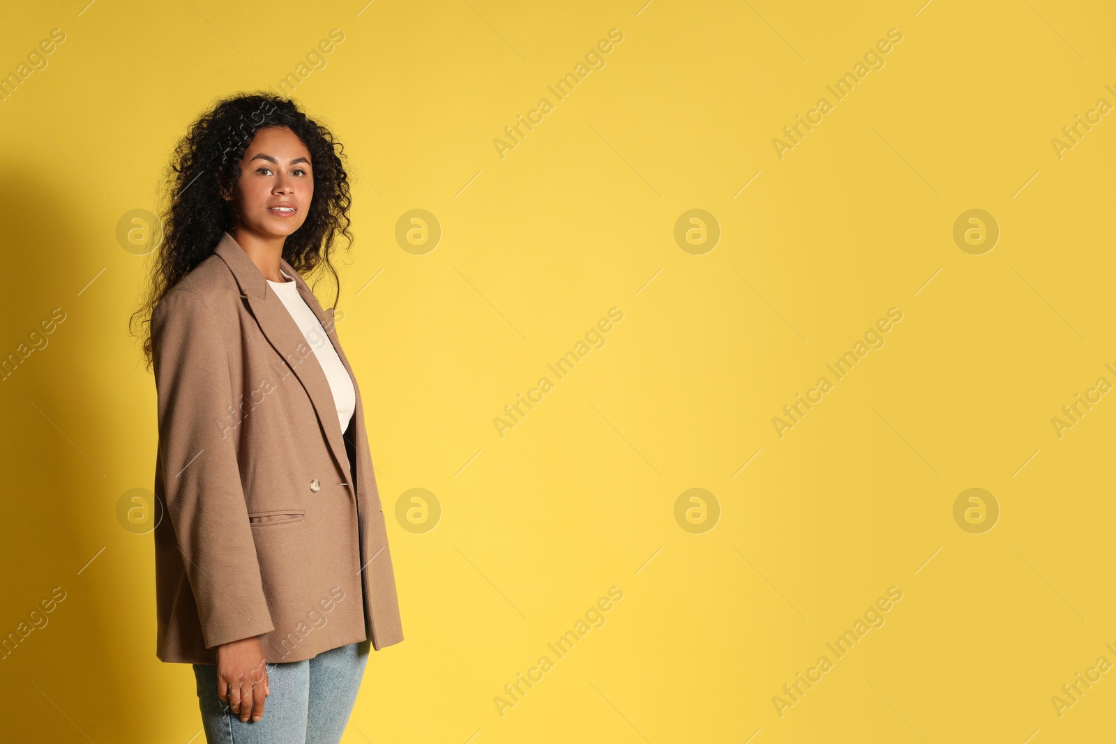 Photo of Beautiful woman in stylish jacket on yellow background, space for text