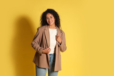 Beautiful woman in stylish jacket on yellow background