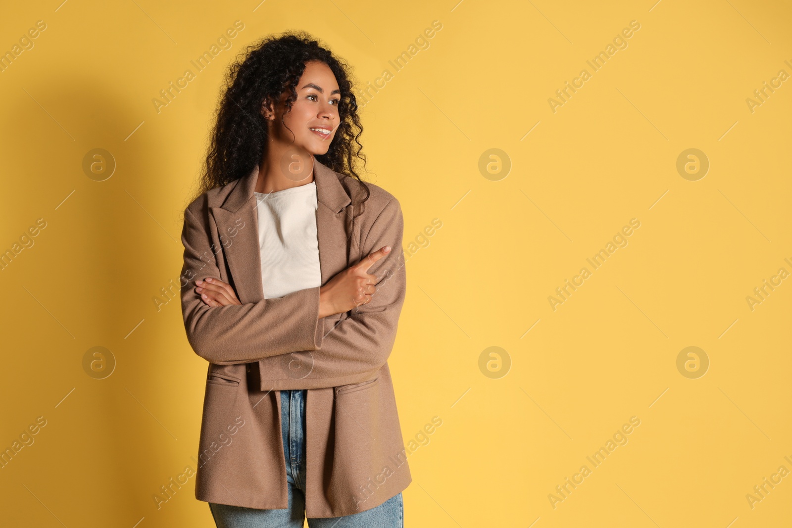 Photo of Beautiful woman in stylish jacket on yellow background, space for text