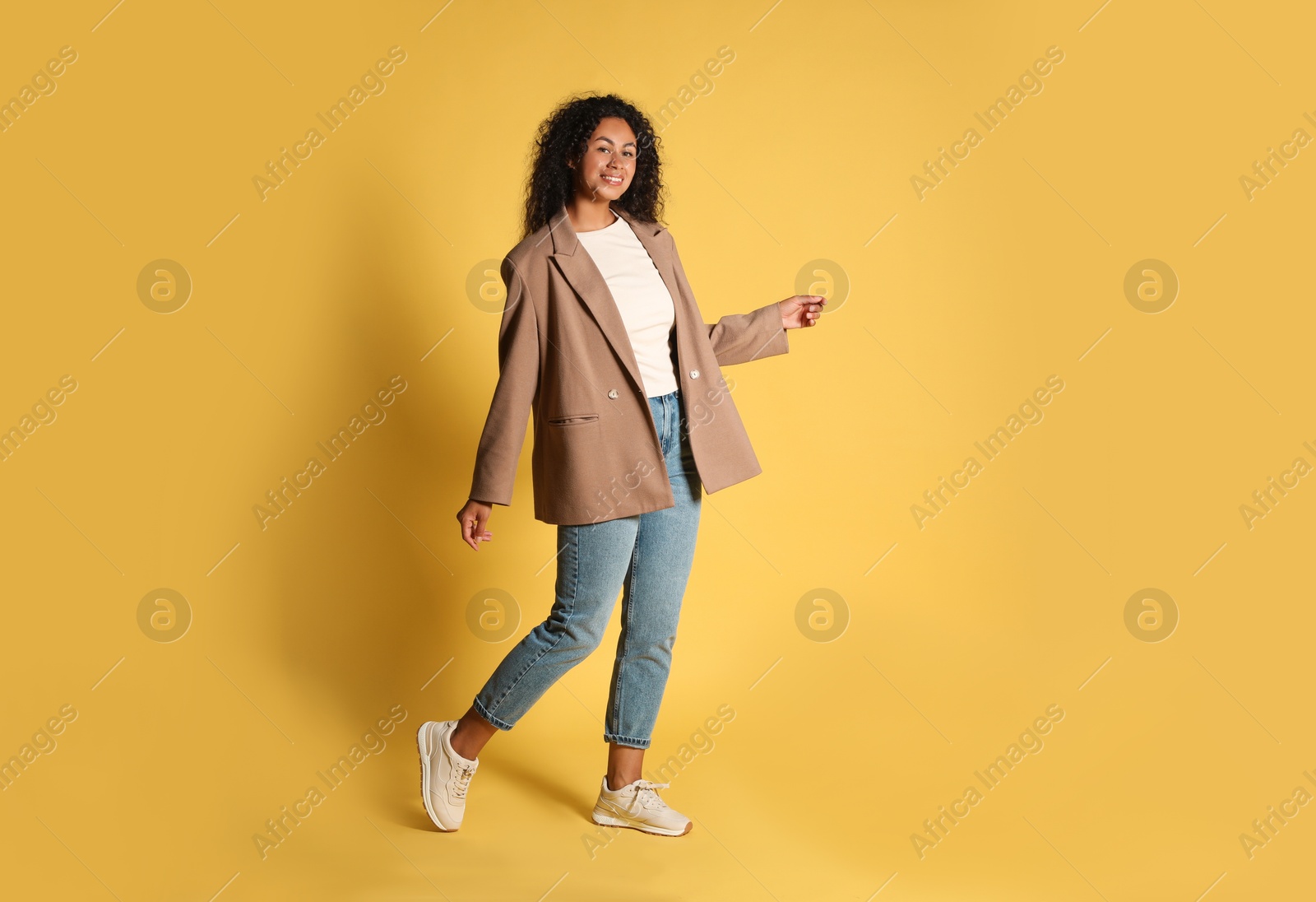 Photo of Beautiful woman in stylish jacket on yellow background