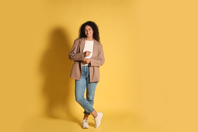 Beautiful woman in stylish jacket on yellow background