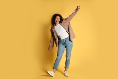 Photo of Beautiful woman in stylish jacket on yellow background