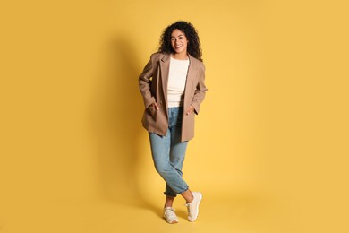 Photo of Beautiful woman in stylish jacket on yellow background