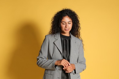 Beautiful woman in stylish jacket on yellow background