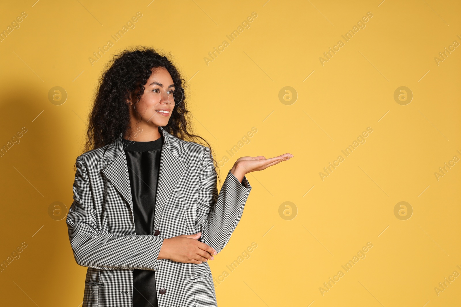 Photo of Beautiful woman in stylish jacket on yellow background, space for text