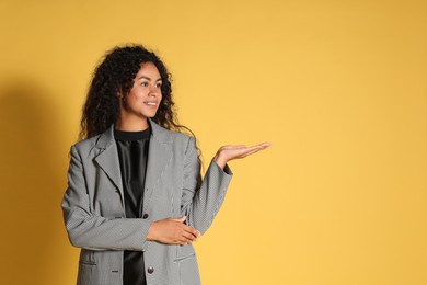 Beautiful woman in stylish jacket on yellow background, space for text