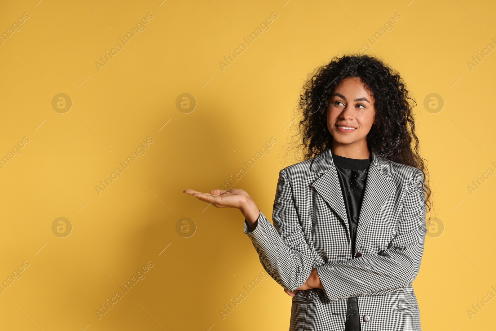 Photo of Beautiful woman in stylish jacket on yellow background, space for text