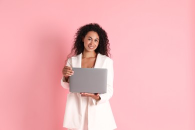 Beautiful woman in stylish jacket with laptop on pink background