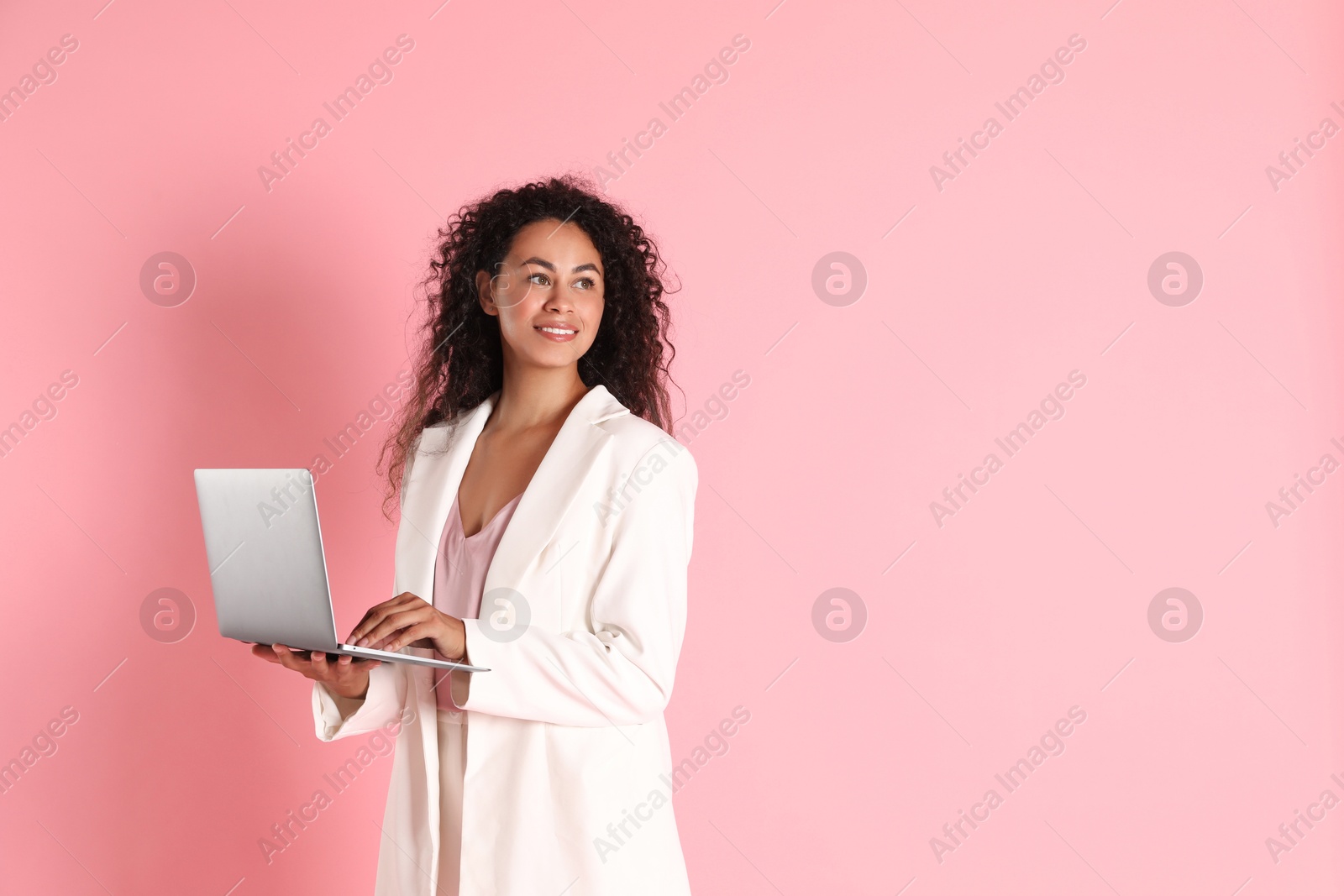 Photo of Beautiful woman in stylish jacket with laptop on pink background, space for text