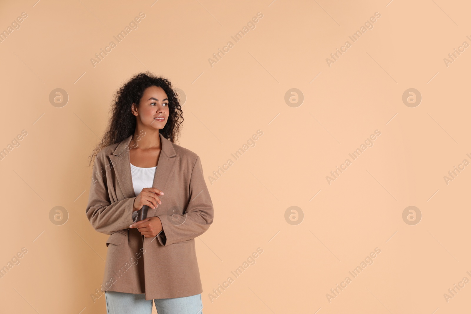 Photo of Beautiful woman in stylish jacket on beige background, space for text