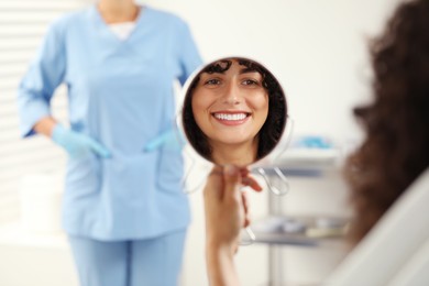 Patient looking in mirror and doctor in clinic, selective focus. Dental veneers