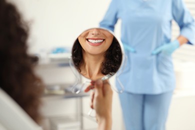 Patient looking in mirror and doctor in clinic, selective focus. Dental veneers