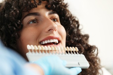 Doctor checking young woman's teeth color in clinic, closeup. Dental veneers