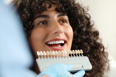 Photo of Doctor checking young woman's teeth color in clinic, closeup. Dental veneers