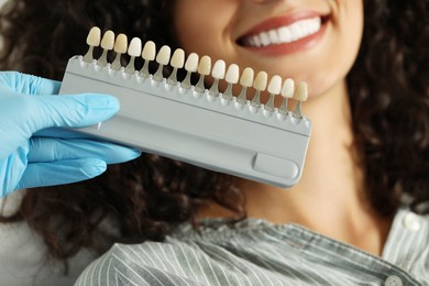 Photo of Doctor checking young woman's teeth color in clinic, closeup. Dental veneers