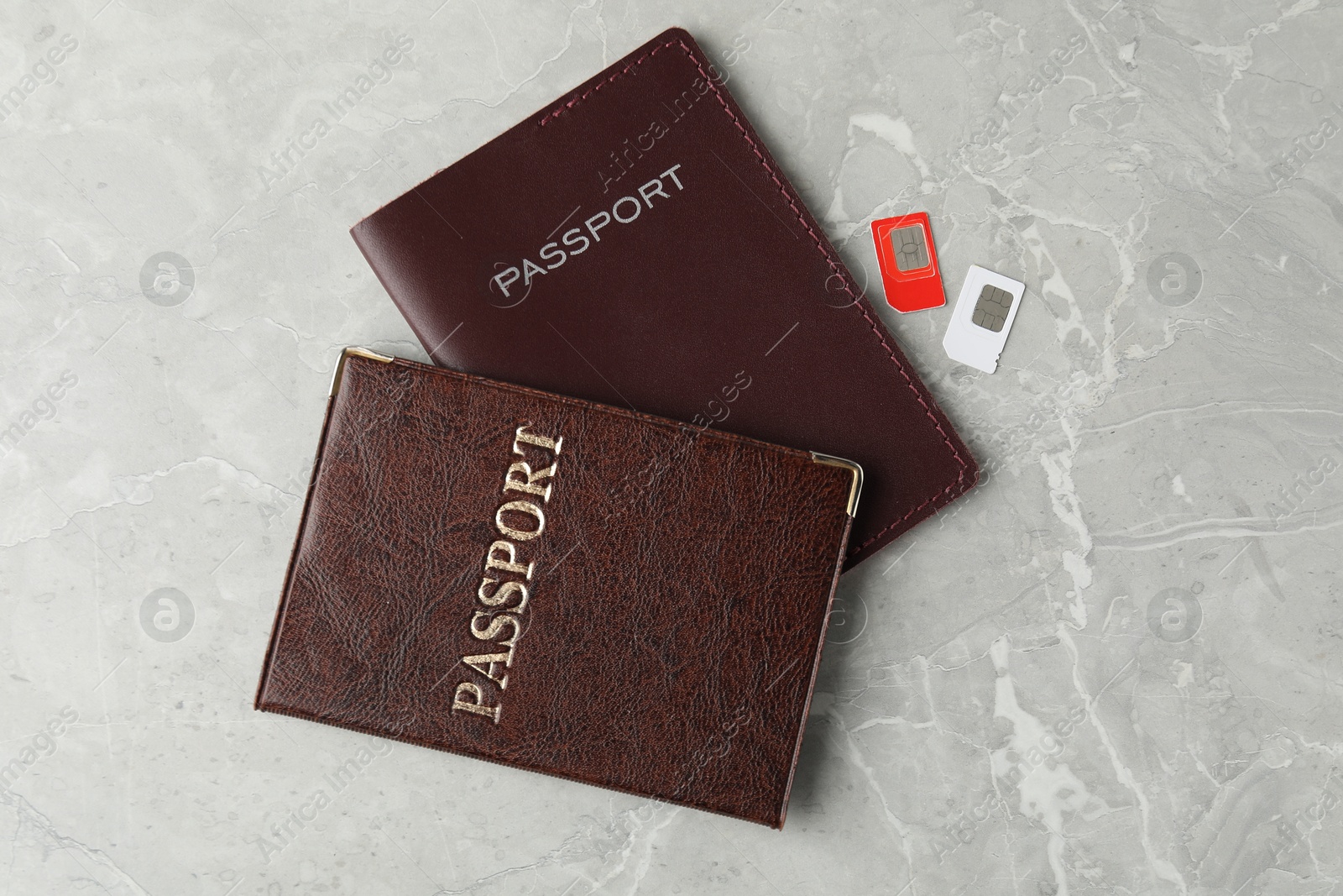 Photo of Passports and SIM cards on grey marble table, flat lay