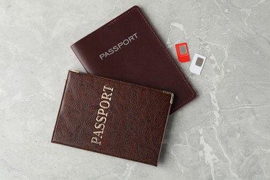 Passports and SIM cards on grey marble table, flat lay