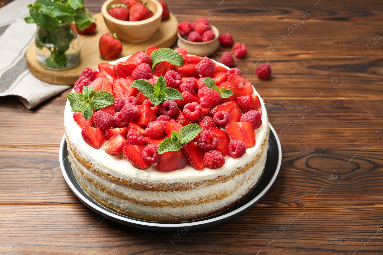 Photo of Tasty sponge cake with fresh berries and mint on wooden table