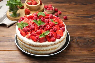 Photo of Tasty sponge cake with fresh berries and mint on wooden table