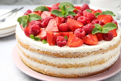 Photo of Tasty sponge cake with fresh berries and mint on light table, closeup