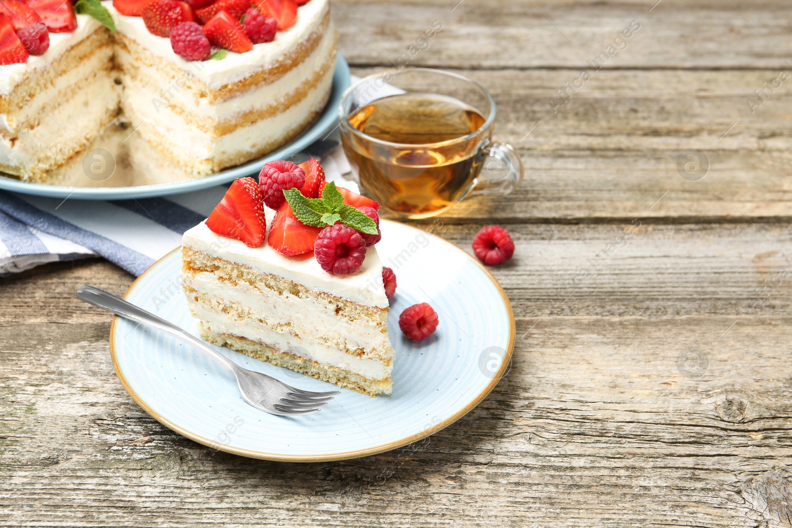 Photo of Tasty sponge cake with fresh berries and mint served on wooden table, space for text