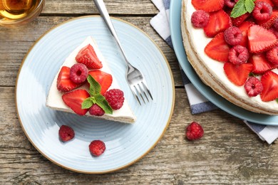 Photo of Tasty sponge cake with fresh berries and mint served on wooden table, flat lay