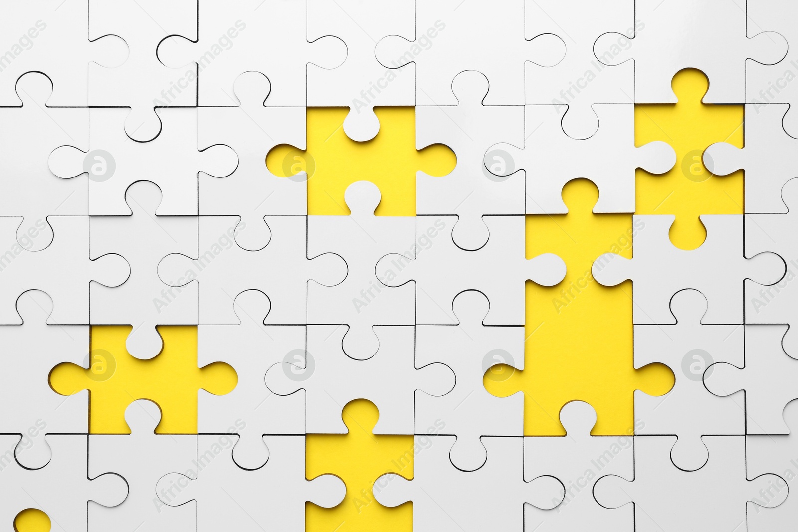 Photo of White puzzle with missing pieces on yellow background, top view