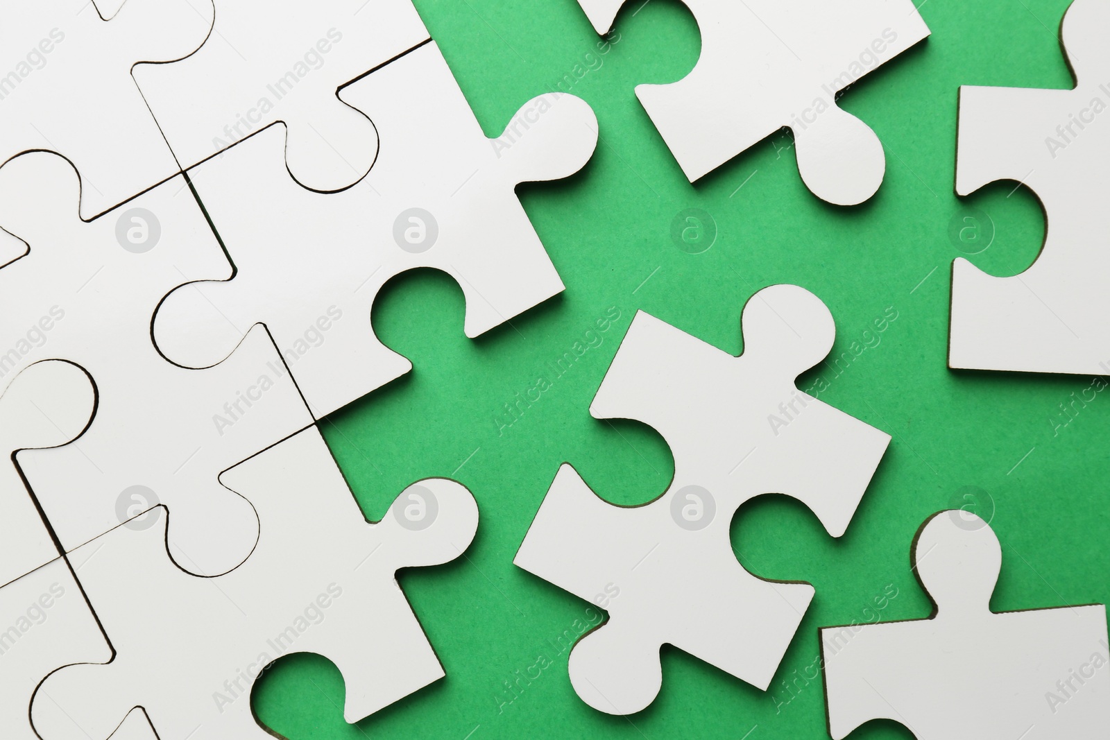 Photo of White puzzle pieces on green background, top view