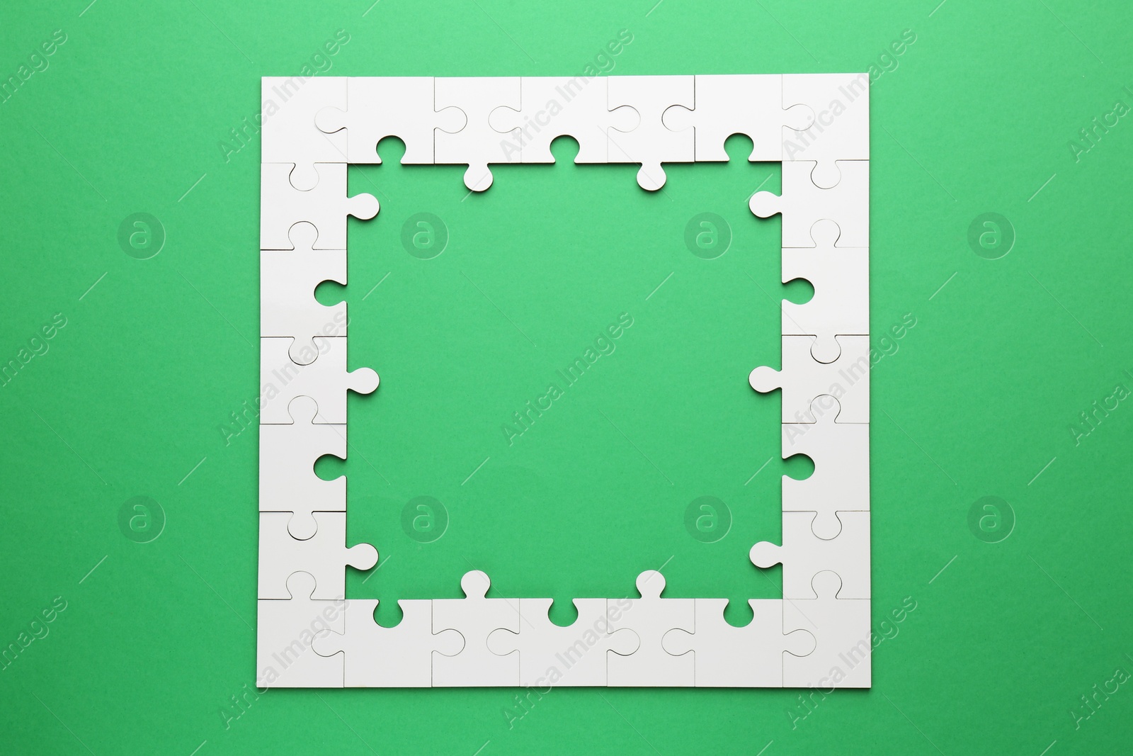 Photo of White puzzle pieces on green background, top view