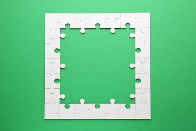 Photo of White puzzle pieces on green background, top view