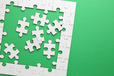 Photo of White puzzle pieces on green background, top view