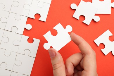 Photo of Woman solving white puzzle on red background, closeup