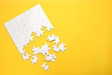 White puzzle pieces on yellow background, top view. Space for text