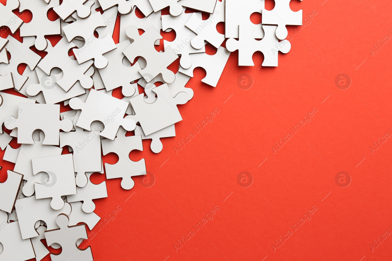 Photo of White puzzle pieces on red background, top view. Space for text