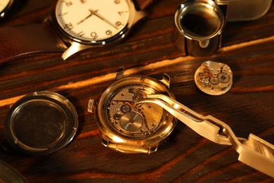 Photo of Mechanism of vintage wrist watch and tool on wooden table, closeup