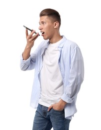 Young man recording voice message via smartphone on white background