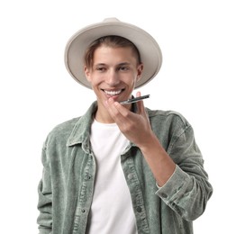 Young man in hat recording voice message via smartphone on white background