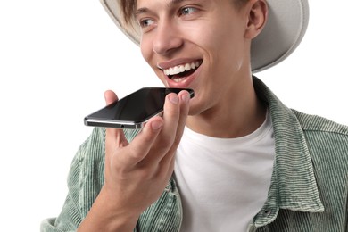 Young man recording voice message via smartphone on white background