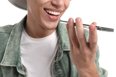 Young man recording voice message via smartphone on white background, closeup