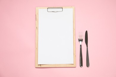 Photo of Clipboard with empty paper for menu design and cutlery on pink table, flat lay