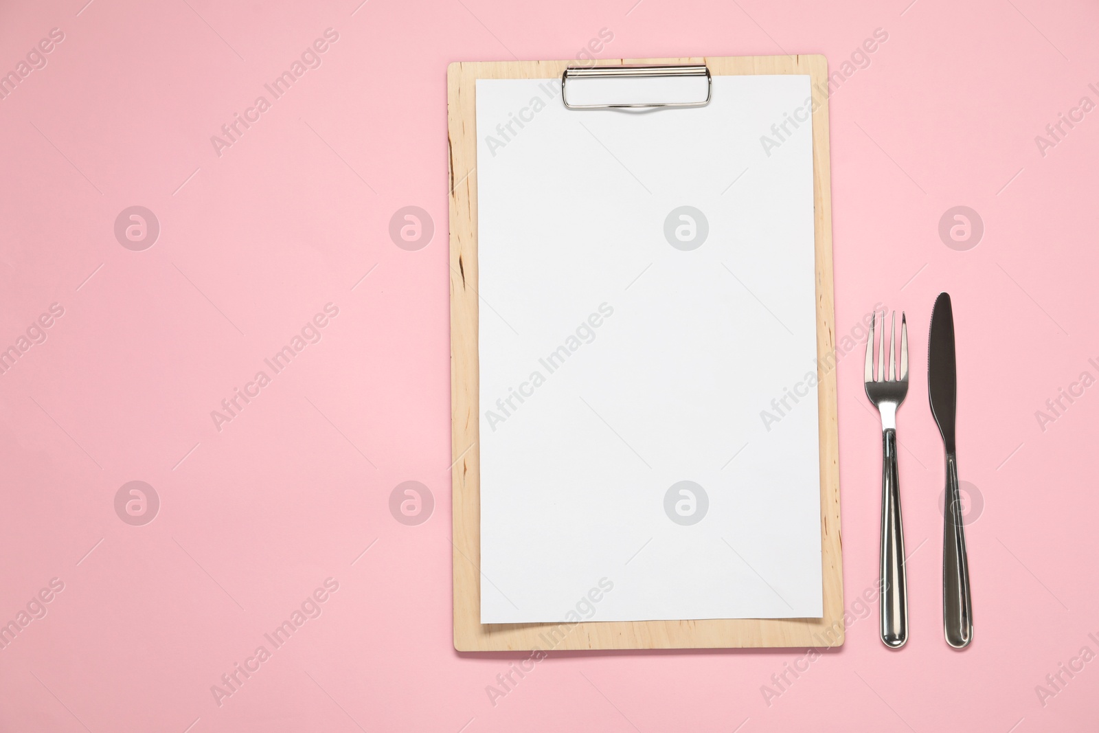 Photo of Clipboard with empty paper for menu design and cutlery on pink table, flat lay. Space for text