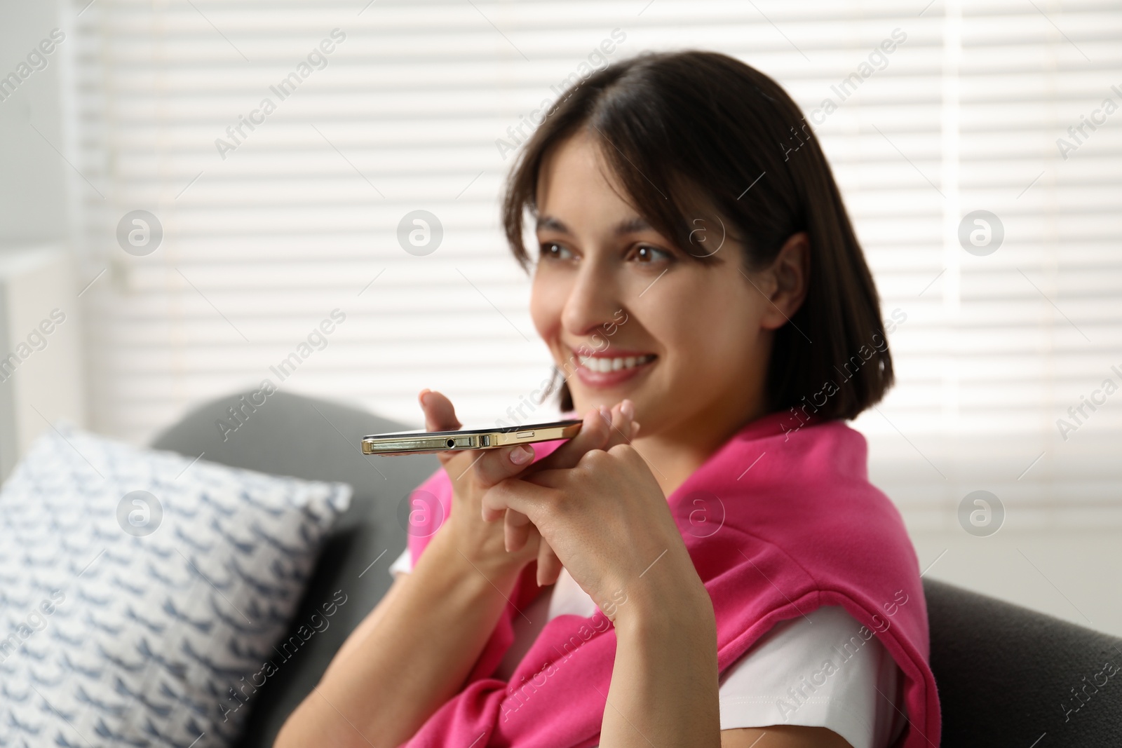 Photo of Beautiful woman recording voice message via smartphone at home